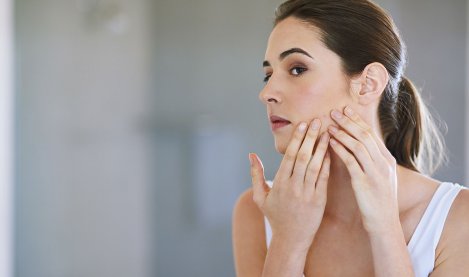 Woman checking her skin in a mirror